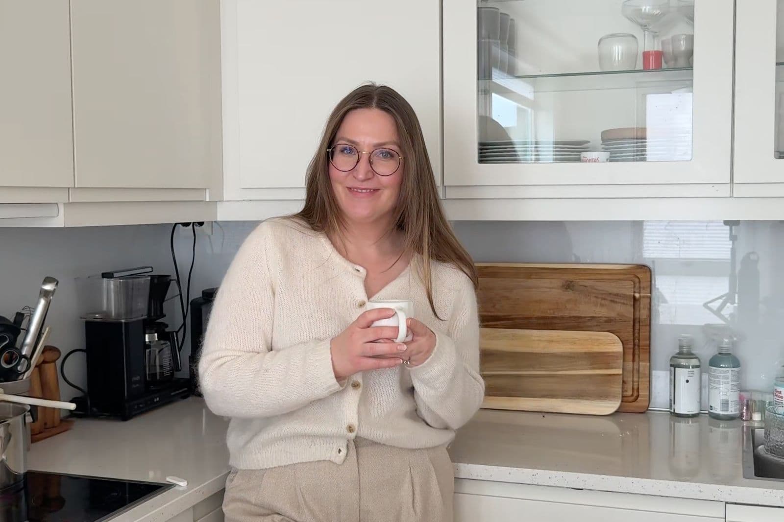 Martine smiler med en kopp på kjøkkenet